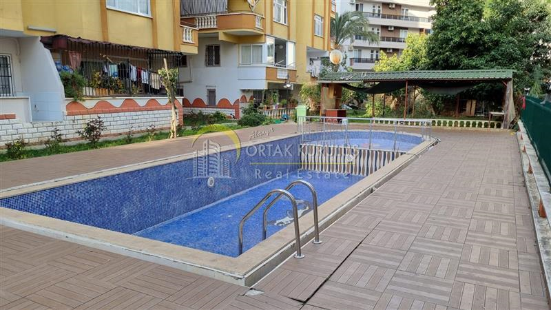 In English: '2+1 Apartment in AYIŞIĞI Building, 150 Meters Away from the Sea in Alanya Tosmur - Outdoor Pool, Security Cameras!'